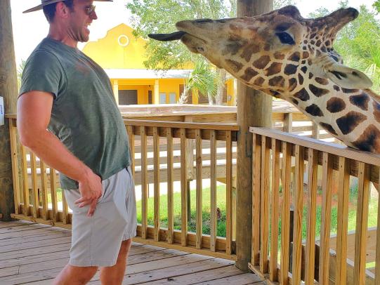 Man feeding giraffe at Alabama Gulf Coast Zoo in Gulf Shores, AL