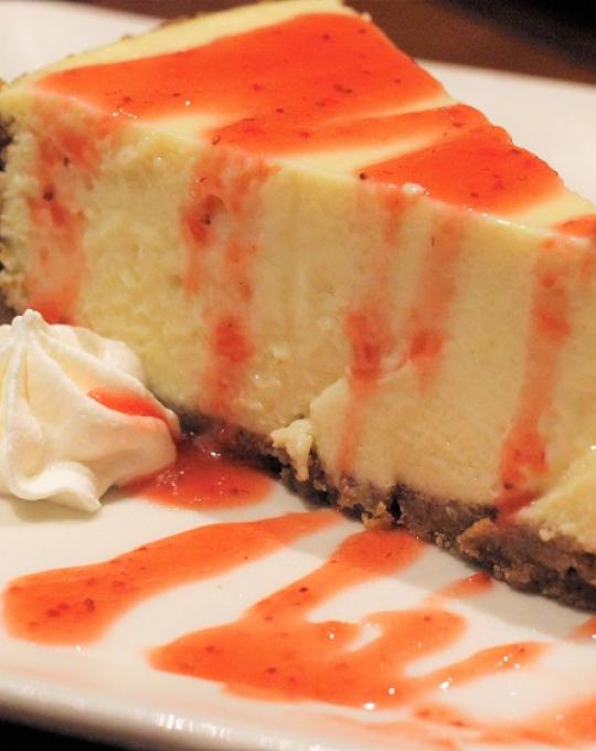 Key lime pie with strawberry syrup and whipped cream on a plate