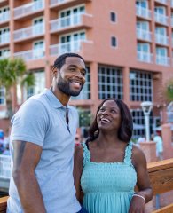 Couple smiling on a boardwalk in front of Perdido Beach Resort in Orange Beach
