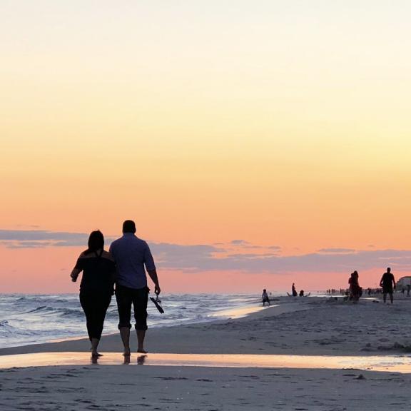 Couple walking on beach at sunset