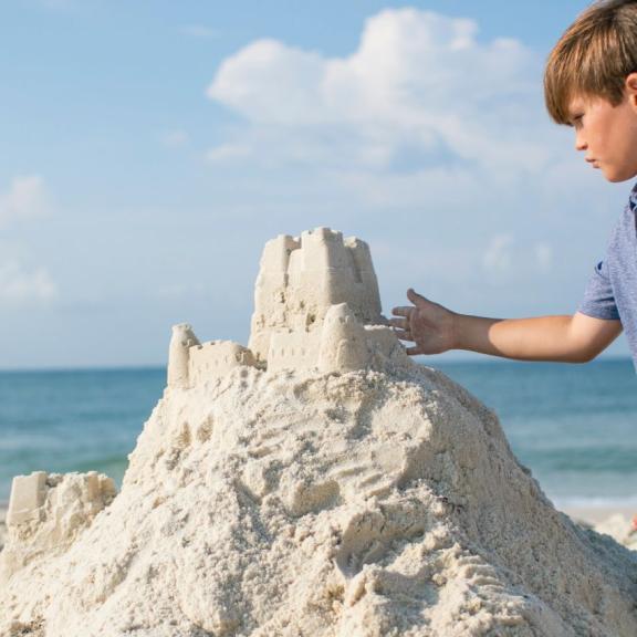 boy building sandcastle in orange beach