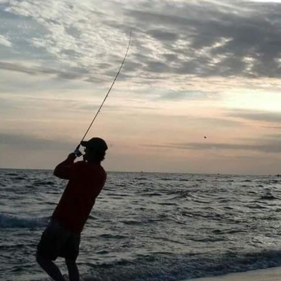 Man fishing on the beach in Alabama at sunset