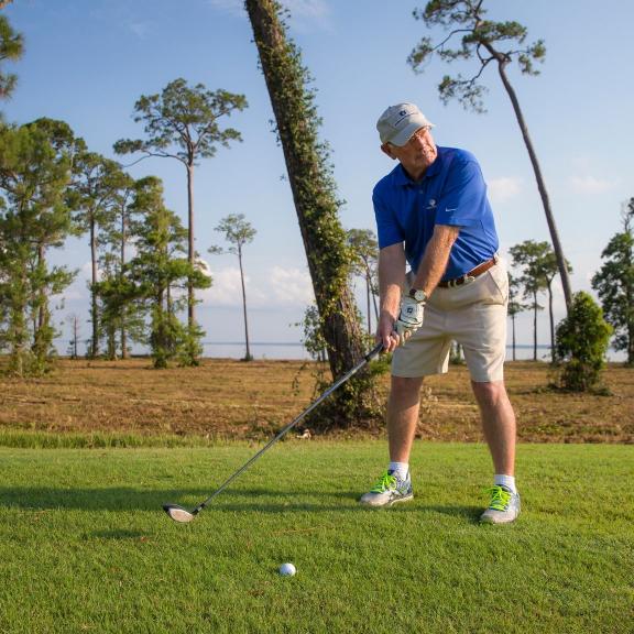 Man swinging a golf club at Peninsula Golf and Racquet Club in Gulf Shores