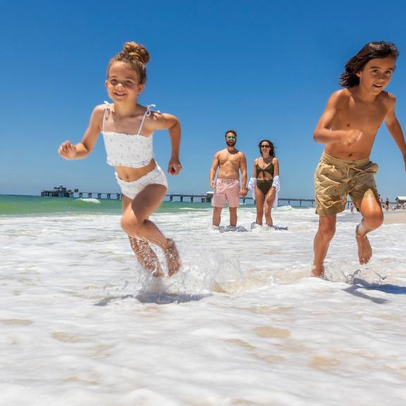 Kids running in front of parents in the surf on the beach in Gulf Shores
