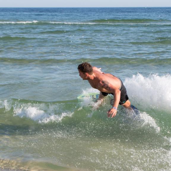 Man skim boarding along the shore of Orange Beach