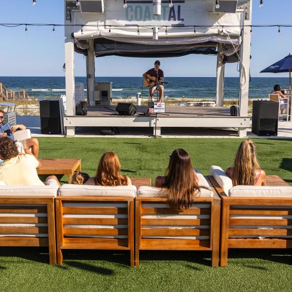 People listening to live music on the grassy lawn at Coastal beachfront restaurant in Orange Beach