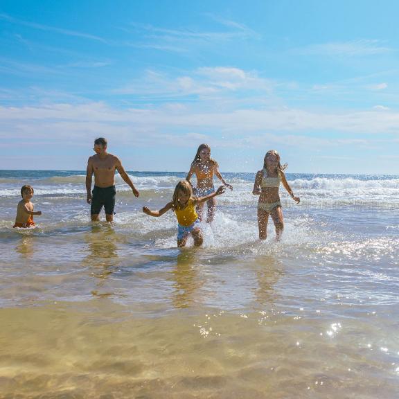 Family splashing in the Gulf while at the beach in Gulf Shores