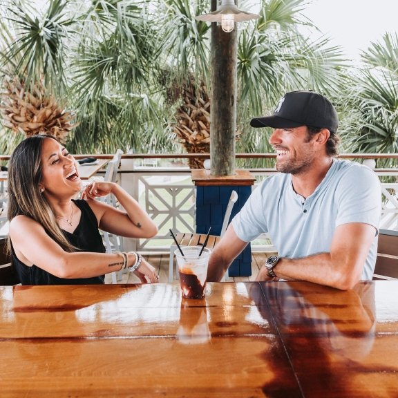 Couple laughing over a bushwacker cocktail at Shipp's Dockside Grill restaurant in Orange Beach