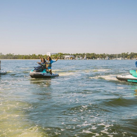 Friends riding Jet Skis in the back bay waters of Orange Beach