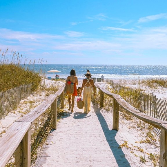 Family walking on a sandy path towards the beach in Gulf Shores