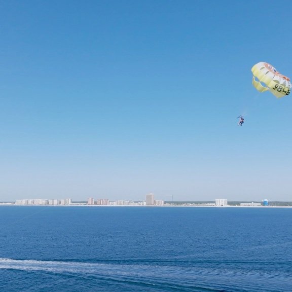scenic view of boat pulling a parasail across the shoreline in Orange Bech