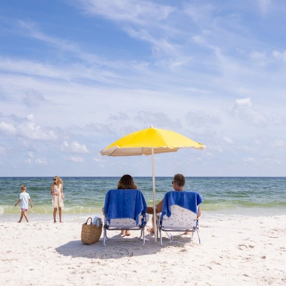 parents watching kid play by the shoreline on the beach in Orange Beach