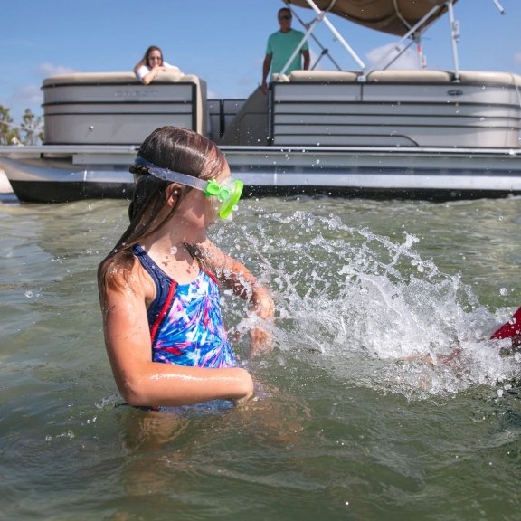 Kids playing in water in front of a pontoon boat rental in Orange Beach