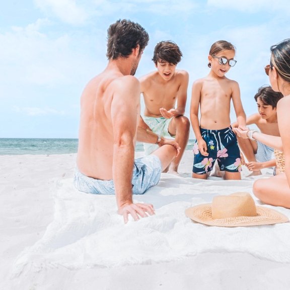 Family sitting on beach blanket near the shore in Orange Beach