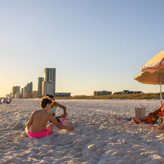 Family relaxing on the beach at sunset in Gulf Shores