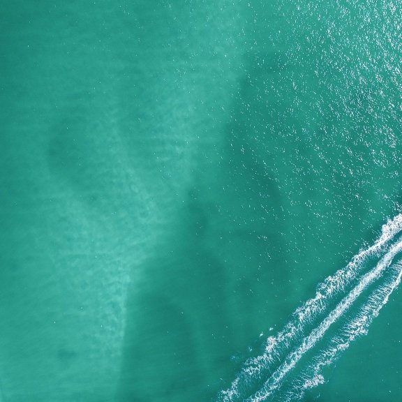 Drone shot of boat cruising in the clear blue waters in Orange Beach