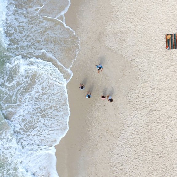 Drone view of family walking along the shoreline in Orange Beach