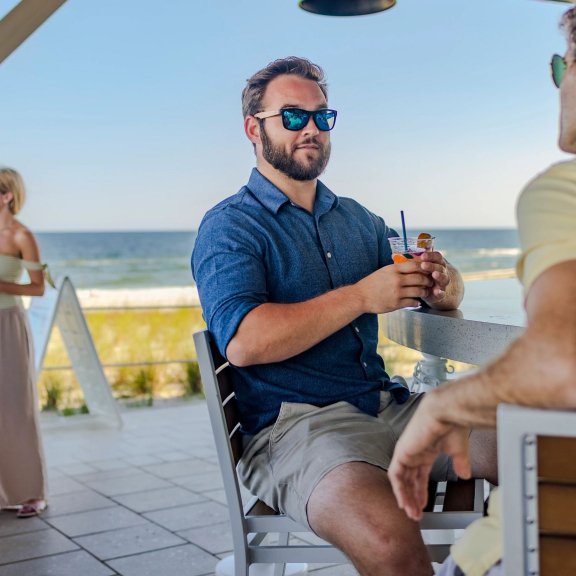 Friends sitting at the beachfront bar at Coastal seafood restaurant in Orange beach