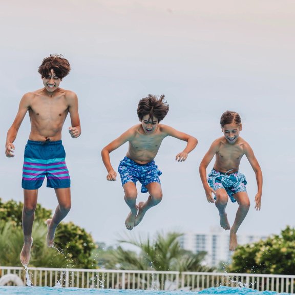 Kids jumping into the pool at The Caribe Resort in Orange Beach