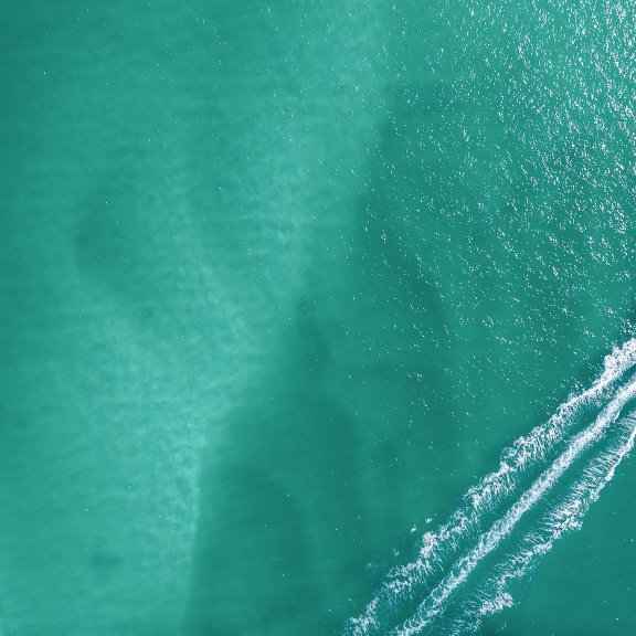Aerial shot of a boat cruising in the turquoise Gulf waters of Orange Beach