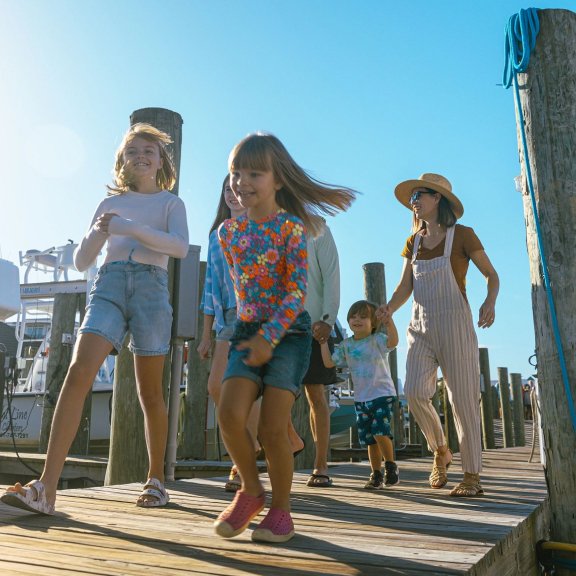 Family running along a marina boardwalk