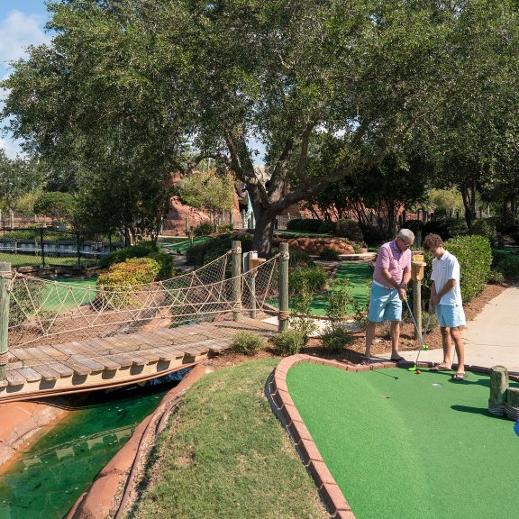 Family playing mini golf at Adventure Island amusement park in Orange Beach