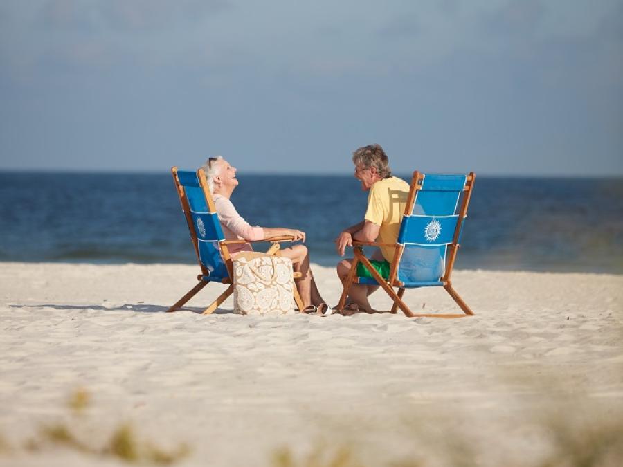 snowbird couple sitting by the water in beach chairs