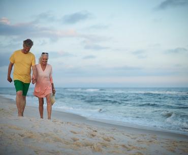 Snowbird couple walking along the shore in Orange Beach
