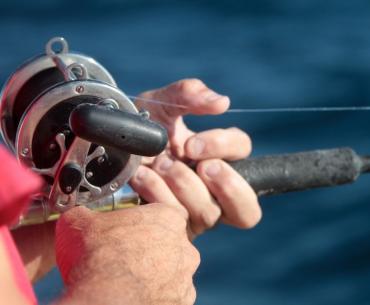 Hand holding a fishing rod on a charter in Orange Beach