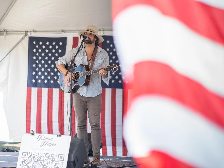 Musician performing in front American flags at Freedom Fest