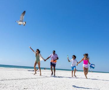 Family running on the beach at Gulf Place, public beach in Gulf Shores