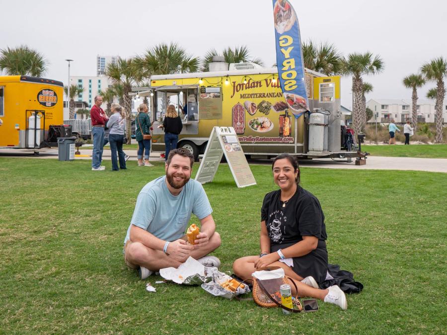Couple sitting on the green lawn at Gulf Place during the Coastal Alabama Food Truck Festival in Gulf Shores