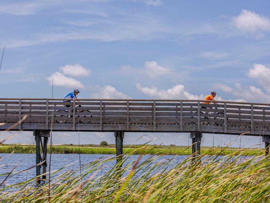 People biking on a boardwalk across Lake Shelby in Gulf State Park