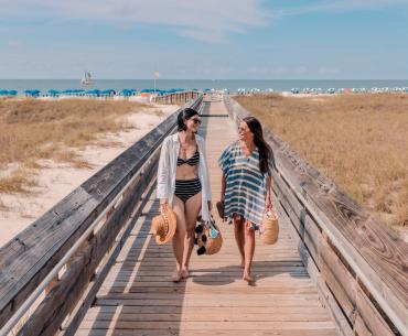 Two women walking on a boardwalk from the Gulf in Orange Beach
