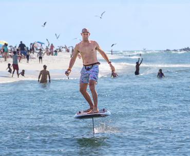 Man riding a foil board near the shore in Orange Beach