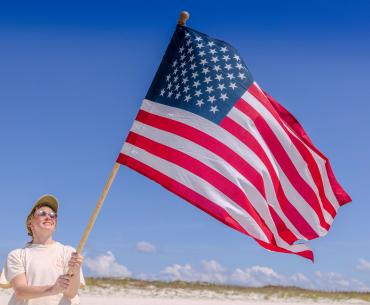 Woman holding an American flag on the beach in Orange Beach