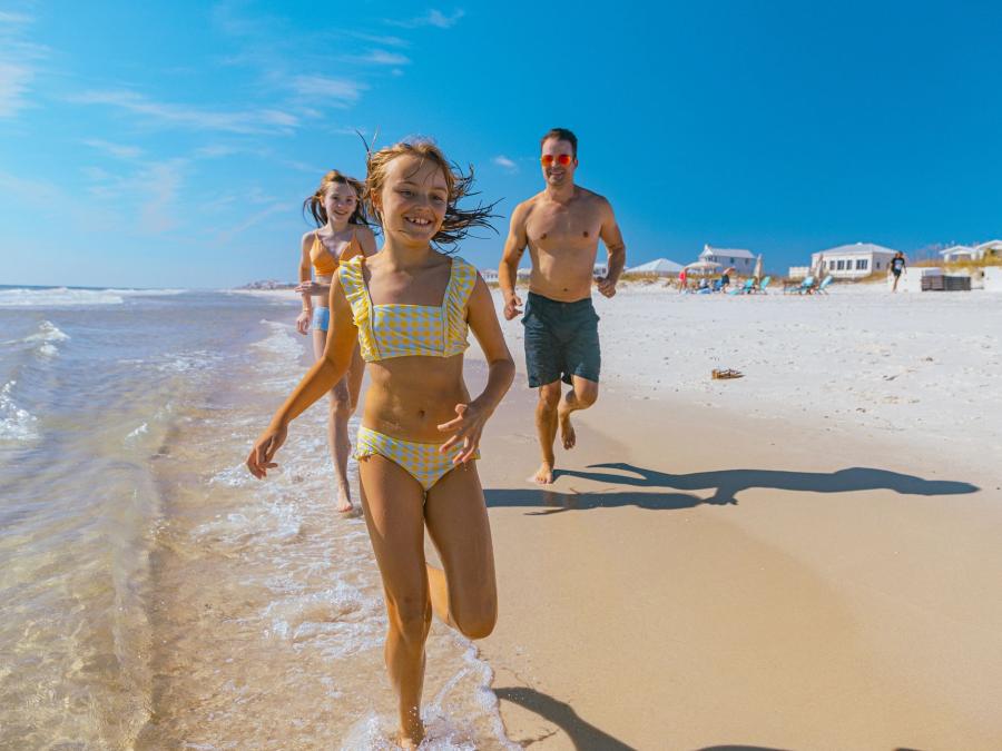 Family running along the water on the beach in Gulf Shores