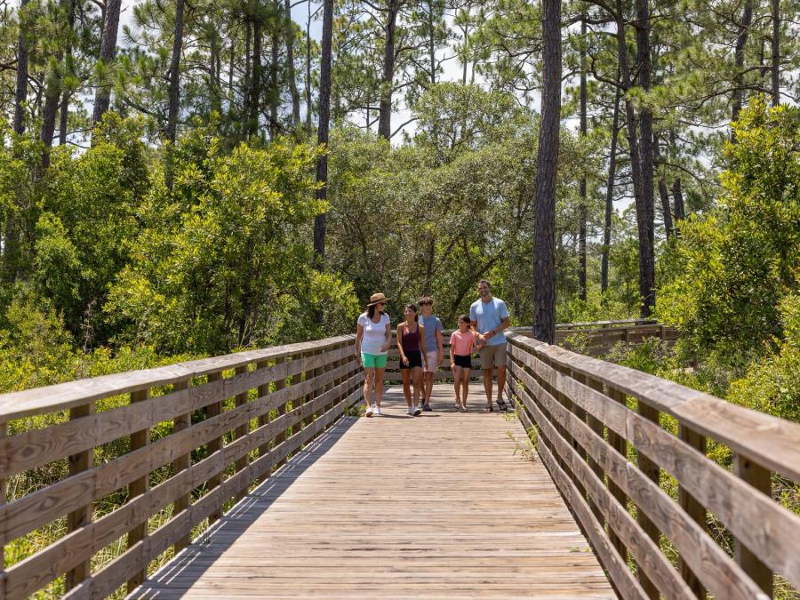 Family walking along a boardwalk on the Hugh S. Branyon Backcountry Trail in Gulf State Park