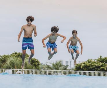 boys jumping into pool at The Caribe Resort in Orange Beach