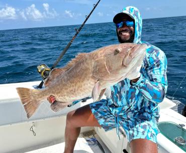 Angler holding a gag grouper caught on a fishing charter in Orange Beach