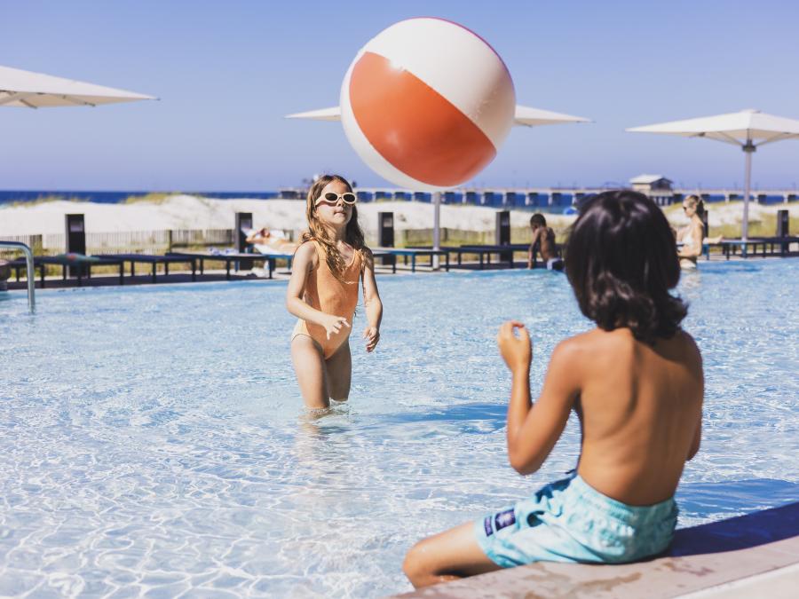 Two kids playing with a beach ball in the pool