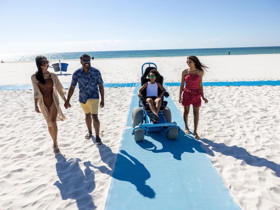 Family using the wheelchair accessible beach mat at the beach in gulf shores