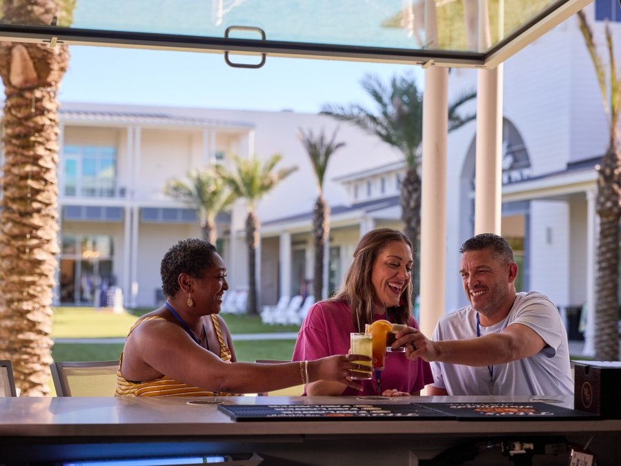Friends drinking at the outside bar at Tee Off at The Wharf in Orange Beach