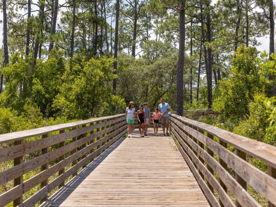 Family walking along scenic boardwalk trail in Gulf State Park