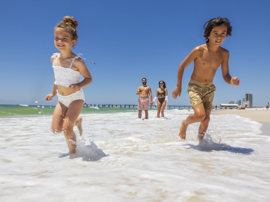 Kids running along the shore on the beach in Gulf Shores