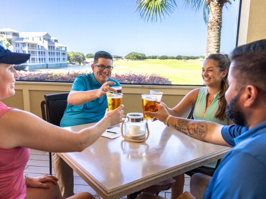 Friends cheersing beers at Kiva Dunes Grill in Fort Morgan