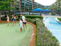 family playing mini golf next to a lazy river