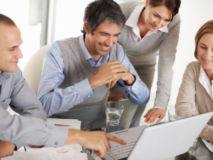 employees gathered looking at computer