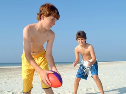 Boys play football on Alabama's white sand beaches