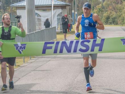 Runner crosses Finish Line at Kaiser Realty Coastal Half Marathon in Orange Beach
